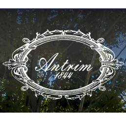 Antrim 1844 white logo with Antrim 1844 in cursive on background with trees